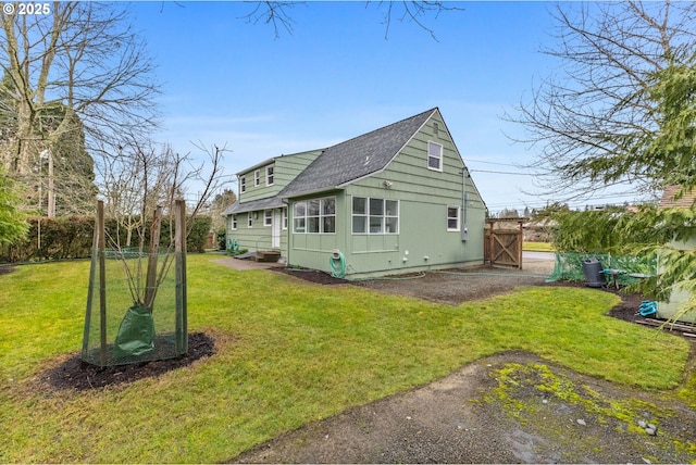 back of house with a lawn and roof with shingles