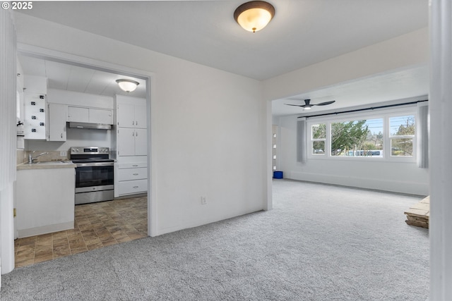 kitchen with carpet floors, stainless steel electric range, a sink, light countertops, and white cabinets