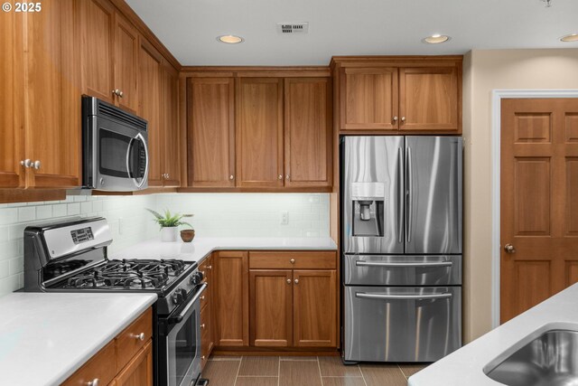 4873 NW Promenade Ter Unit 122, Portland, OR 97229 - kitchen featuring stainless steel appliances, light countertops, brown cabinets, tasteful backsplash, and recessed lighting