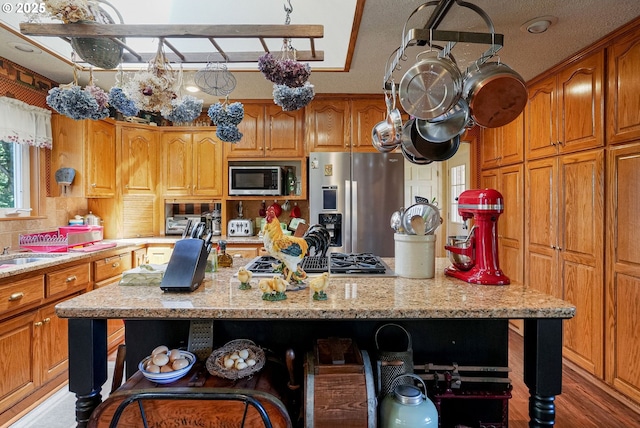 4269 Victor Point Rd, Silverton, OR 97381 - kitchen featuring stainless steel appliances, a center island with sink, open shelves, light stone counters, and brown cabinetry