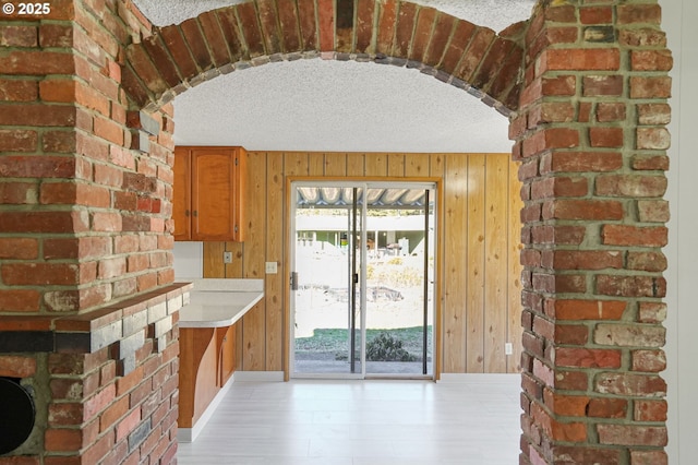 interior space featuring light hardwood / wood-style floors, a textured ceiling, and wood walls