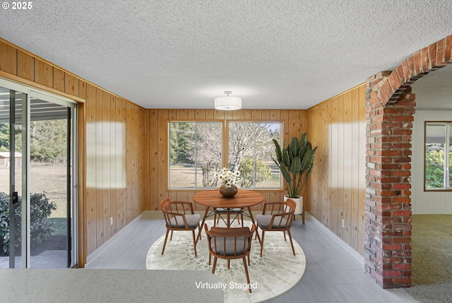 dining space featuring a textured ceiling and wood walls