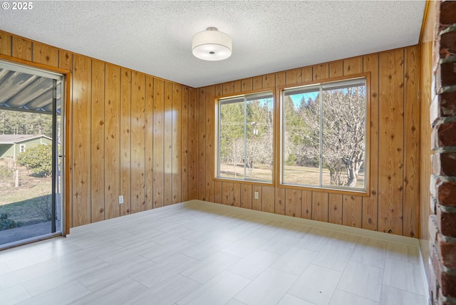 unfurnished room featuring a textured ceiling and wood walls