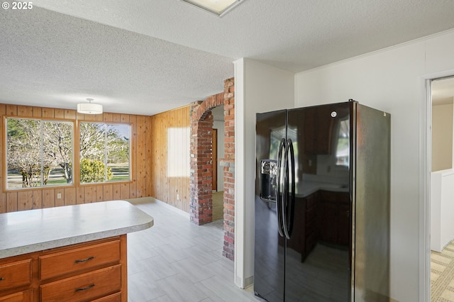 kitchen featuring wooden walls, a textured ceiling, and black fridge