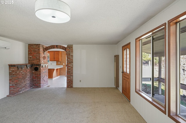 interior space with an AC wall unit, light carpet, and a textured ceiling