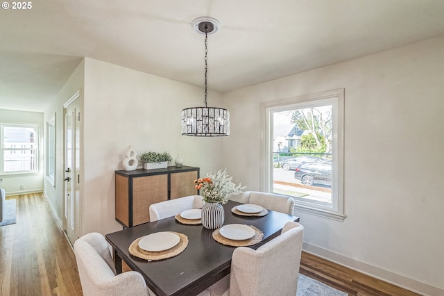dining space featuring a chandelier, wood finished floors, and baseboards