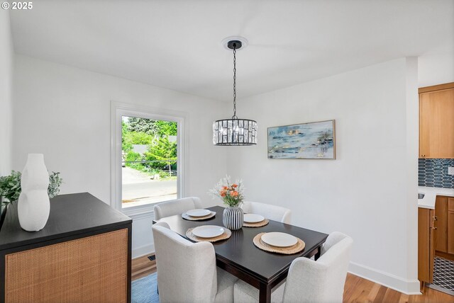 dining space featuring a chandelier, light wood-type flooring, and baseboards
