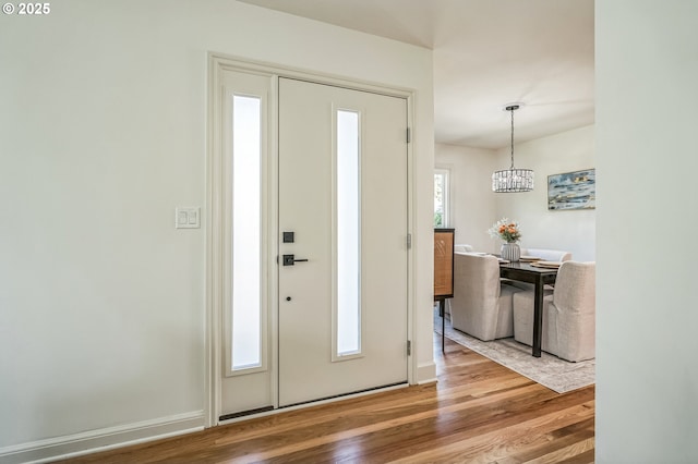 foyer featuring wood finished floors, a chandelier, and baseboards