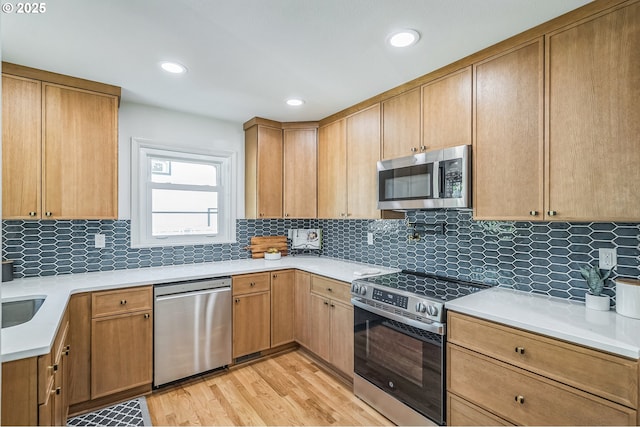 kitchen with stainless steel appliances, light wood-style floors, light countertops, tasteful backsplash, and recessed lighting