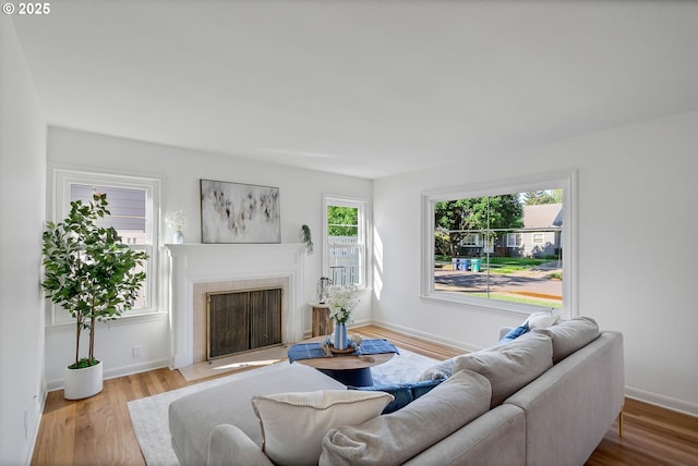 living room featuring a fireplace with flush hearth, wood finished floors, and baseboards