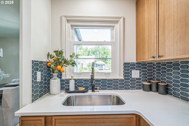 kitchen with a sink, light countertops, tasteful backsplash, and brown cabinets