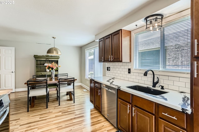 319 NE Hyde Cir, Hillsboro, OR 97124 - kitchen featuring stainless steel dishwasher, a sink, decorative backsplash, light countertops, and light wood-style floors