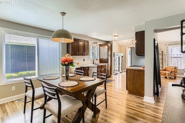 319 NE Hyde Cir, Hillsboro, OR 97124 - dining room featuring light wood finished floors, baseboards, a chandelier, and a textured ceiling