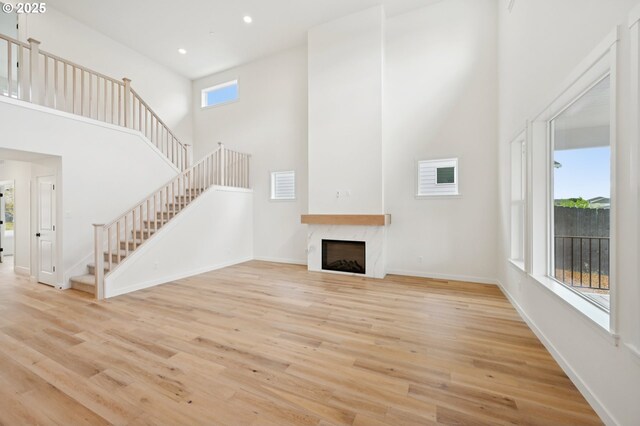 310 W 20th Way, La Center, WA 98629 - unfurnished living room with plenty of natural light, a fireplace, stairway, a towering ceiling, and recessed lighting
