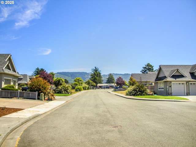 7205 Edge Cliff Dr, Brookings, OR 97415 - view of asphalt road featuring curbs, sidewalks, a residential view, and a mountain view