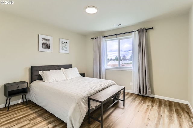 bedroom featuring baseboards, visible vents, and wood finished floors