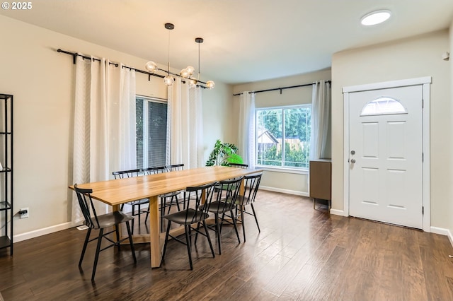 dining area with dark wood-style floors, an inviting chandelier, and baseboards