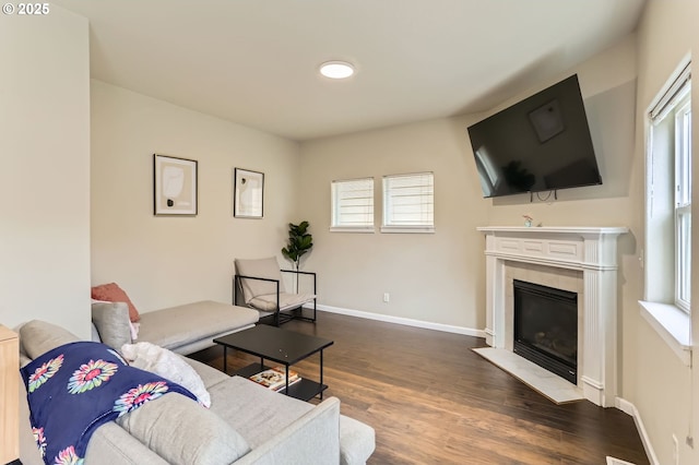 living room featuring a tile fireplace, dark wood finished floors, and baseboards