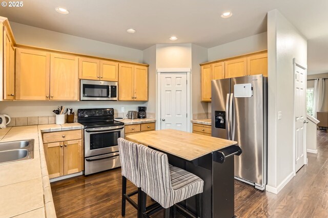 kitchen featuring stainless steel appliances, light brown cabinets, dark wood finished floors, and recessed lighting