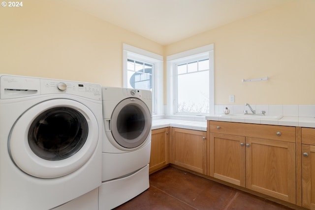 clothes washing area featuring cabinets, washing machine and dryer, and sink