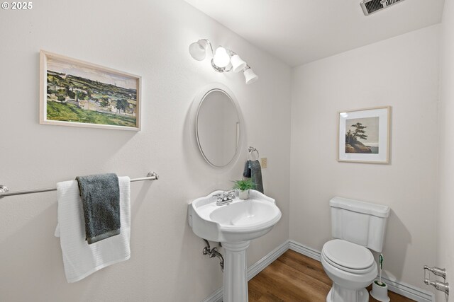 bathroom with toilet, wood finished floors, and baseboards