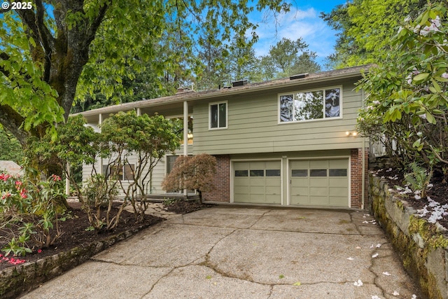 split foyer home with brick siding, a garage, and concrete driveway