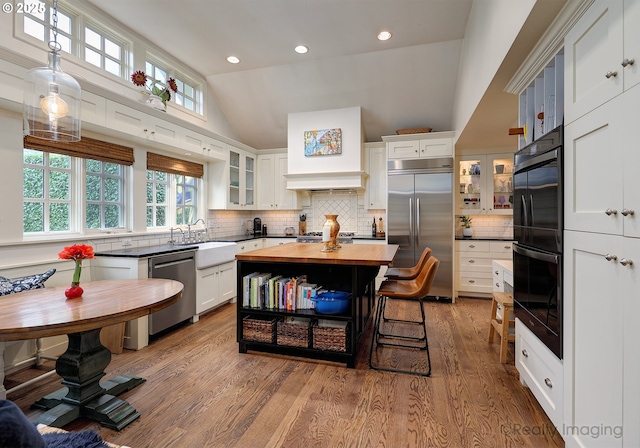 kitchen featuring appliances with stainless steel finishes, a center island, sink, white cabinetry, and butcher block counters