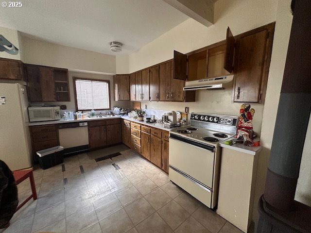 kitchen featuring light tile patterned floors, white appliances, dark brown cabinets, beam ceiling, and sink