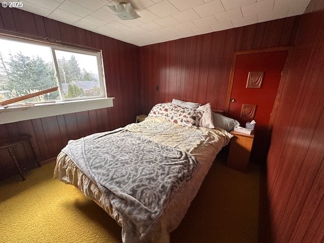 bedroom with carpet floors and wooden walls