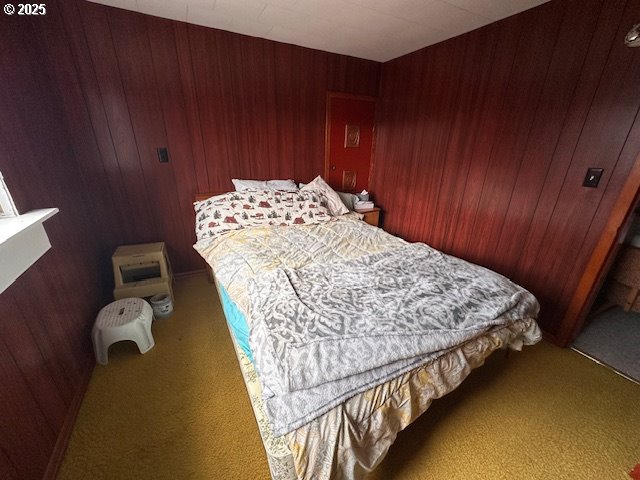 bedroom with carpet and wood walls