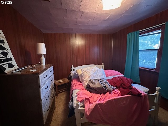 carpeted bedroom with wood walls