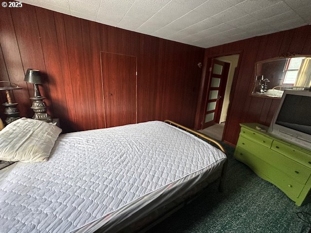 bedroom with carpet flooring and wood walls