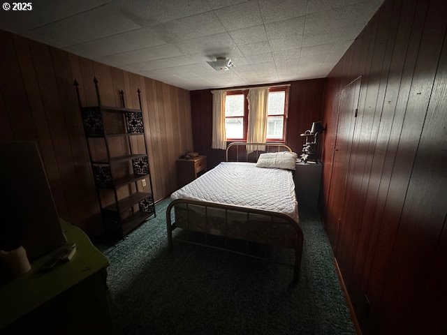 carpeted bedroom with wooden walls