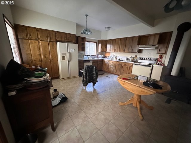 kitchen with light tile patterned flooring, pendant lighting, beam ceiling, and white appliances