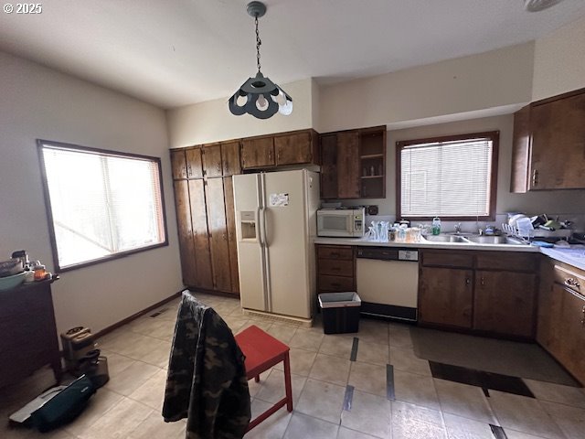 kitchen featuring decorative light fixtures, plenty of natural light, sink, and white appliances