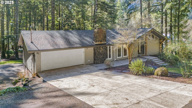 view of front facade featuring an attached garage, driveway, and roof with shingles