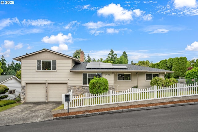 1520 SE 109th Ave, Portland, OR 97216 - tri-level home with an attached garage, roof mounted solar panels, driveway, stone siding, and a fenced front yard