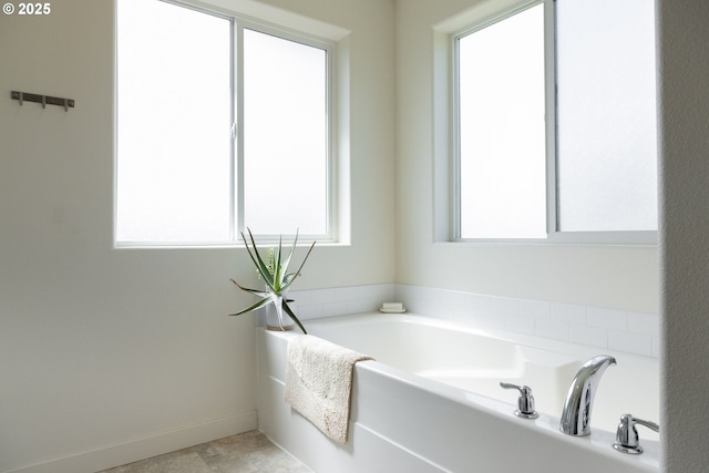full bath featuring plenty of natural light, a garden tub, and baseboards