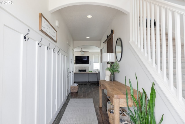 corridor featuring dark wood-type flooring, recessed lighting, and arched walkways