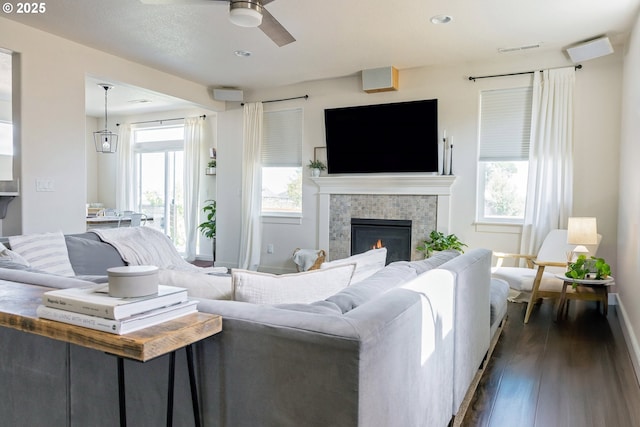 living area with dark wood-style floors, a ceiling fan, a tiled fireplace, baseboards, and recessed lighting