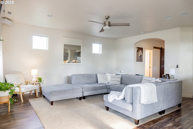 living room featuring arched walkways, ceiling fan, dark wood-type flooring, a barn door, and recessed lighting