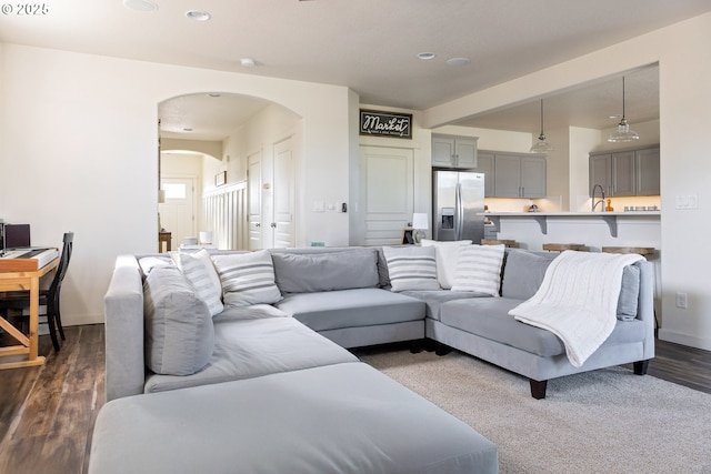 living room with arched walkways, recessed lighting, and dark wood-style flooring