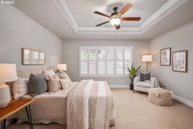 carpeted bedroom featuring a raised ceiling and ceiling fan