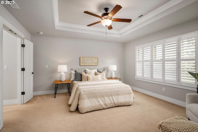 bedroom featuring light carpet, a raised ceiling, and ceiling fan