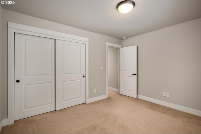 unfurnished bedroom featuring light colored carpet and a closet