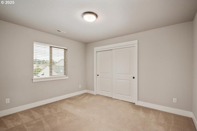 unfurnished bedroom with light carpet and a closet