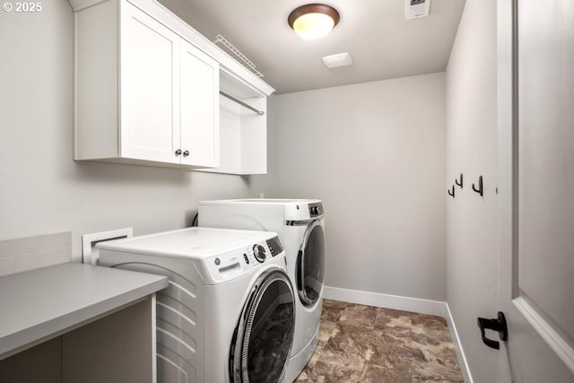 clothes washing area featuring cabinets and washer and clothes dryer