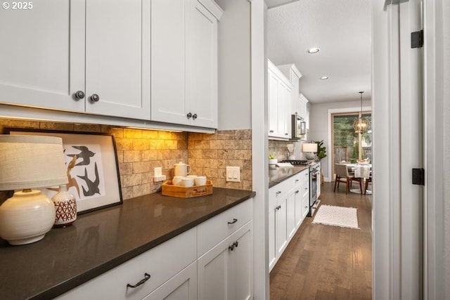 bar featuring white cabinetry, hanging light fixtures, stainless steel appliances, dark hardwood / wood-style flooring, and decorative backsplash