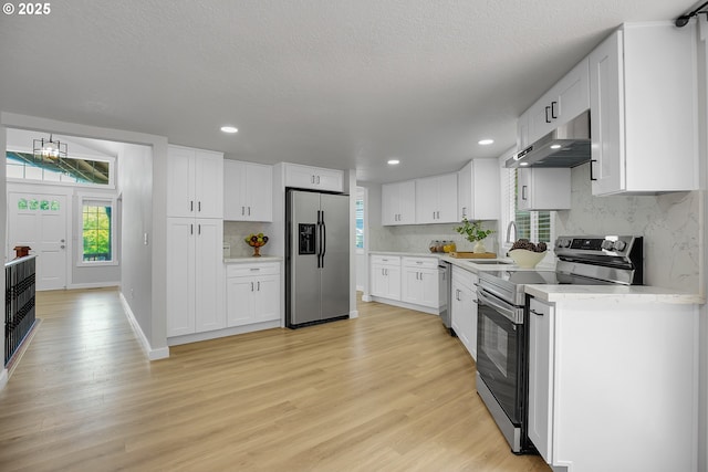 1111 SW Linneman Ave, Gresham, OR 97080 - kitchen with appliances with stainless steel finishes, ventilation hood, light countertops, decorative backsplash, and recessed lighting