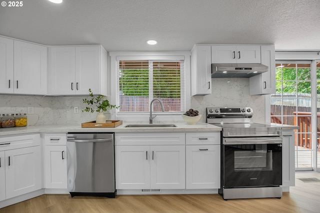 1111 SW Linneman Ave, Gresham, OR 97080 - kitchen featuring stainless steel appliances, exhaust hood, light wood-style flooring, white cabinetry, and a textured ceiling